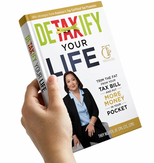 A hand holding a copy of Detaxify Your Life